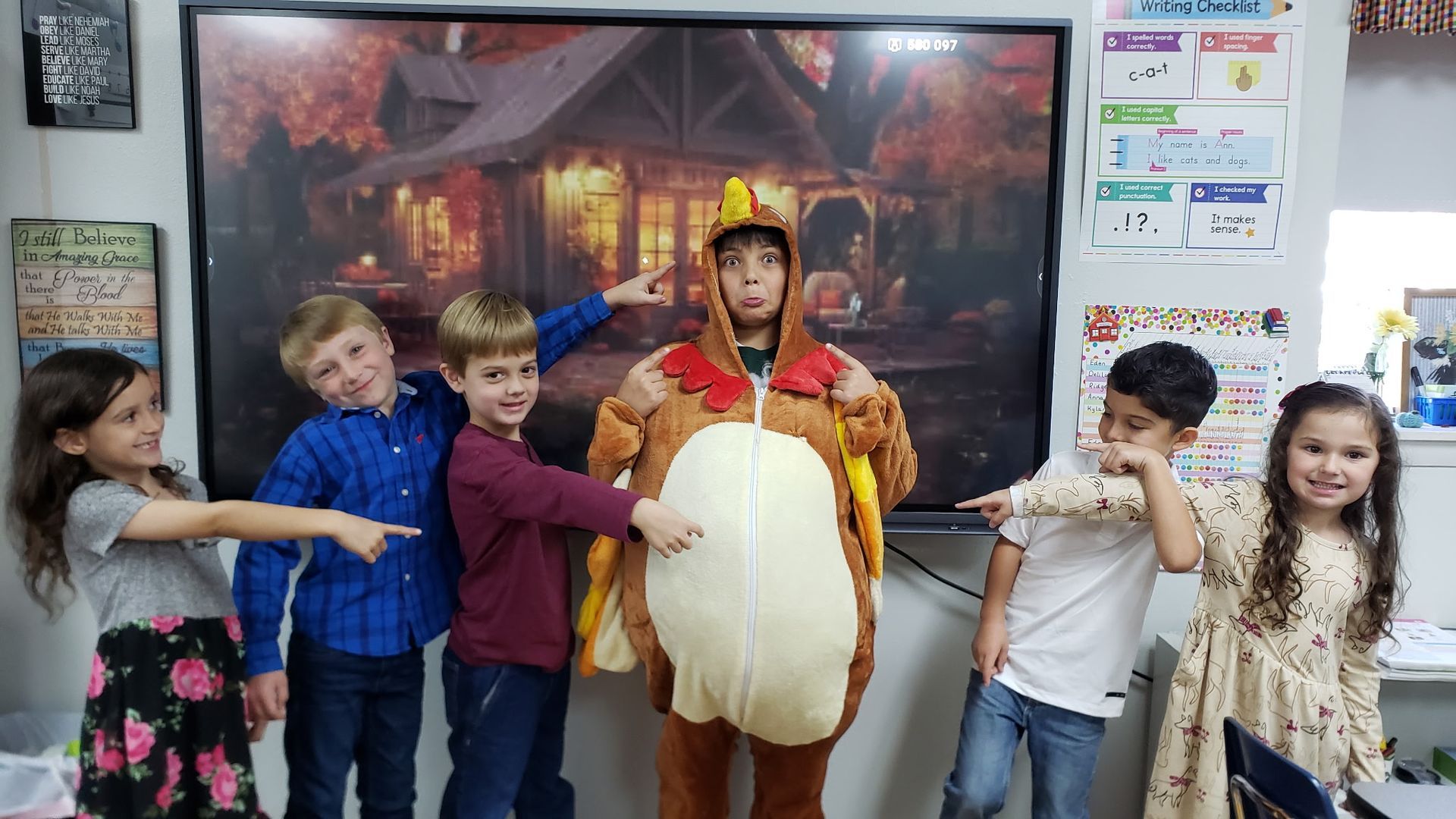 Children pointing at a person in a turkey costume in front of a fall-themed projection.