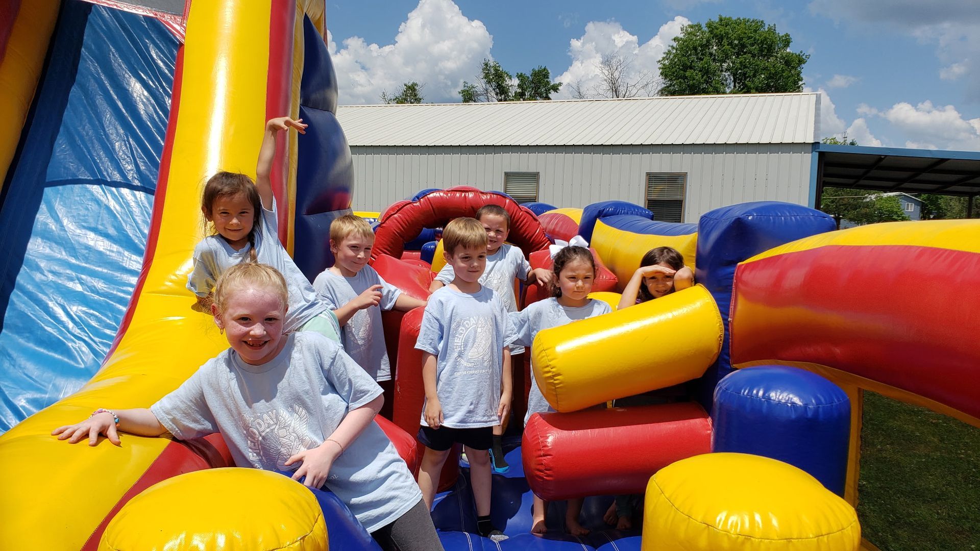 Children playing in colorful inflatable obstacle course outdoors.