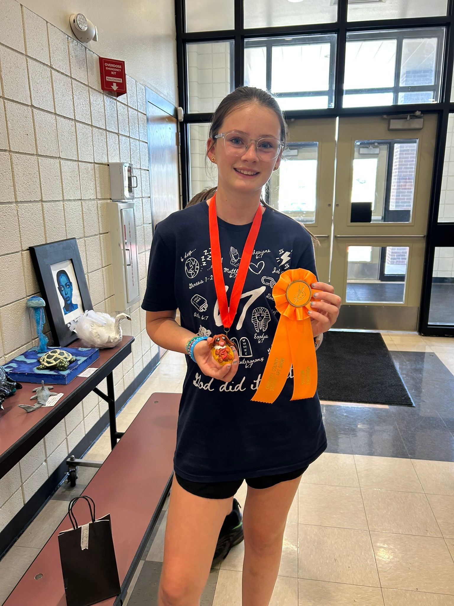 Young student holding an orange ribbon and medal in a school hallway