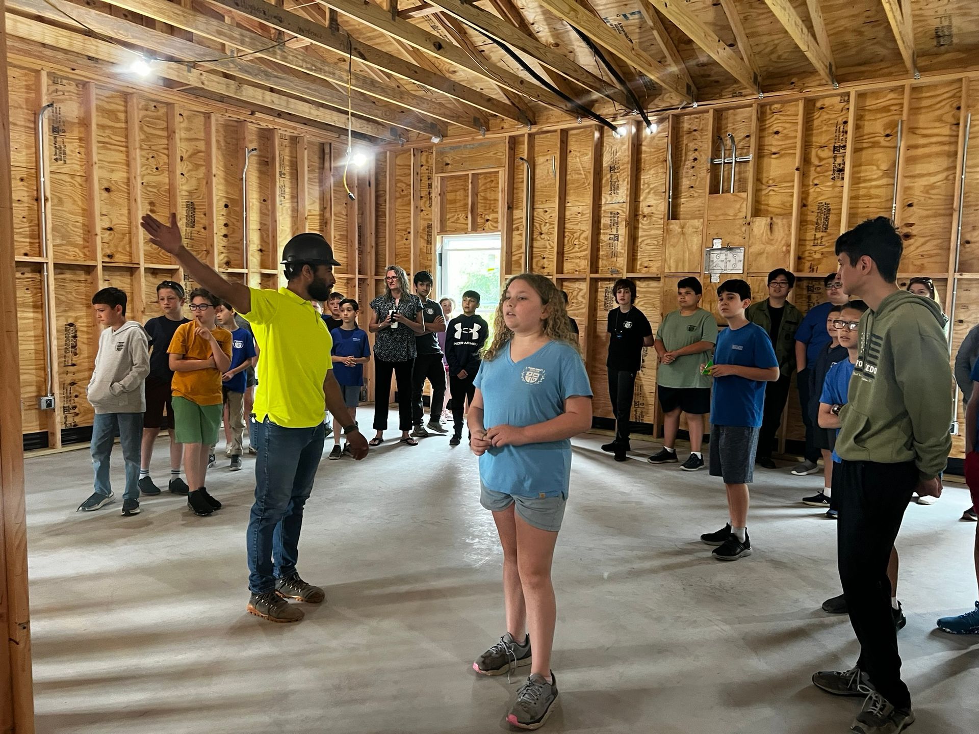 Group of people standing in a framed wooden room, appearing to practice or attend a class.
