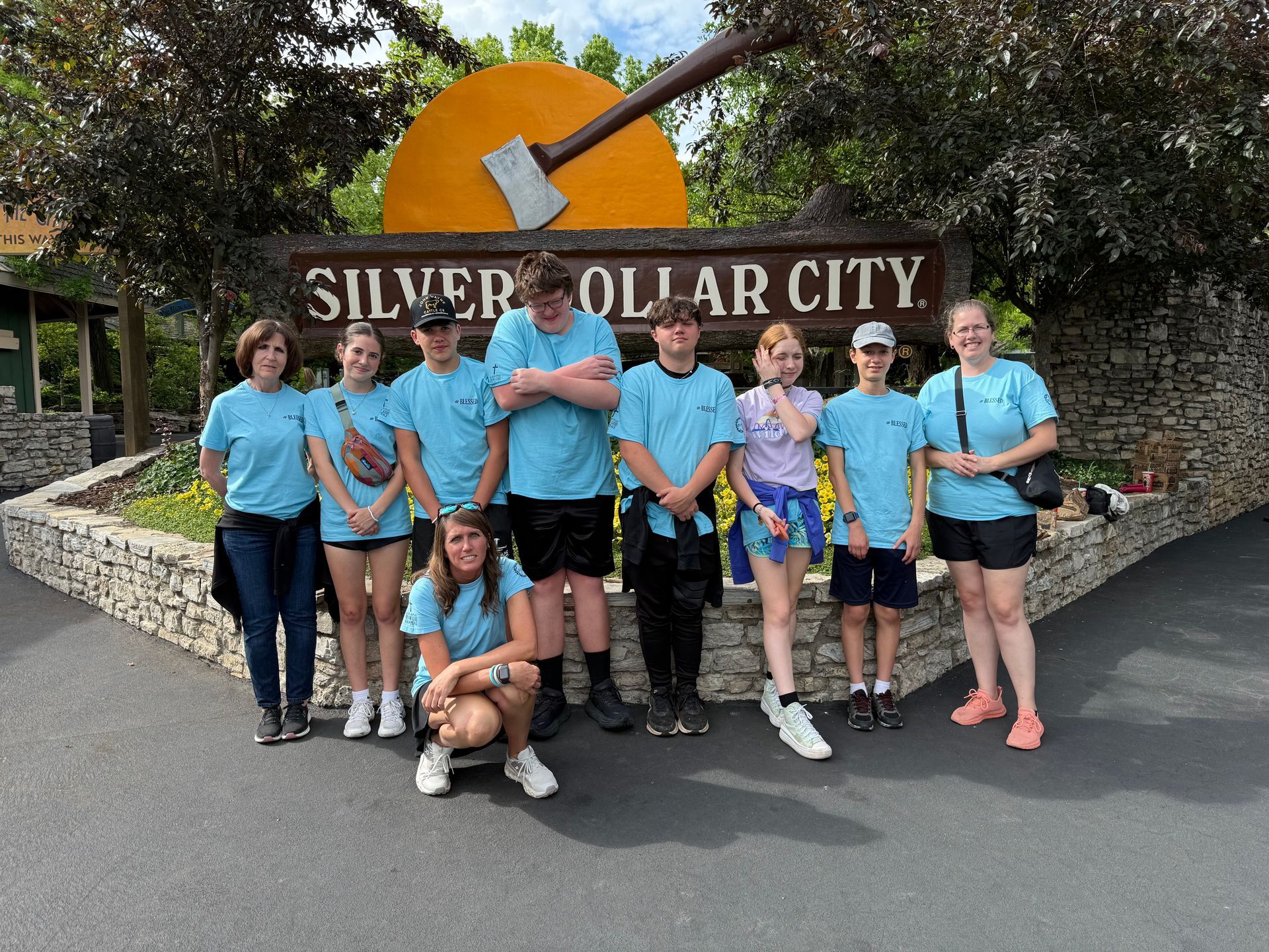 Group of people in blue shirts pose in front of the Silver Dollar City sign.