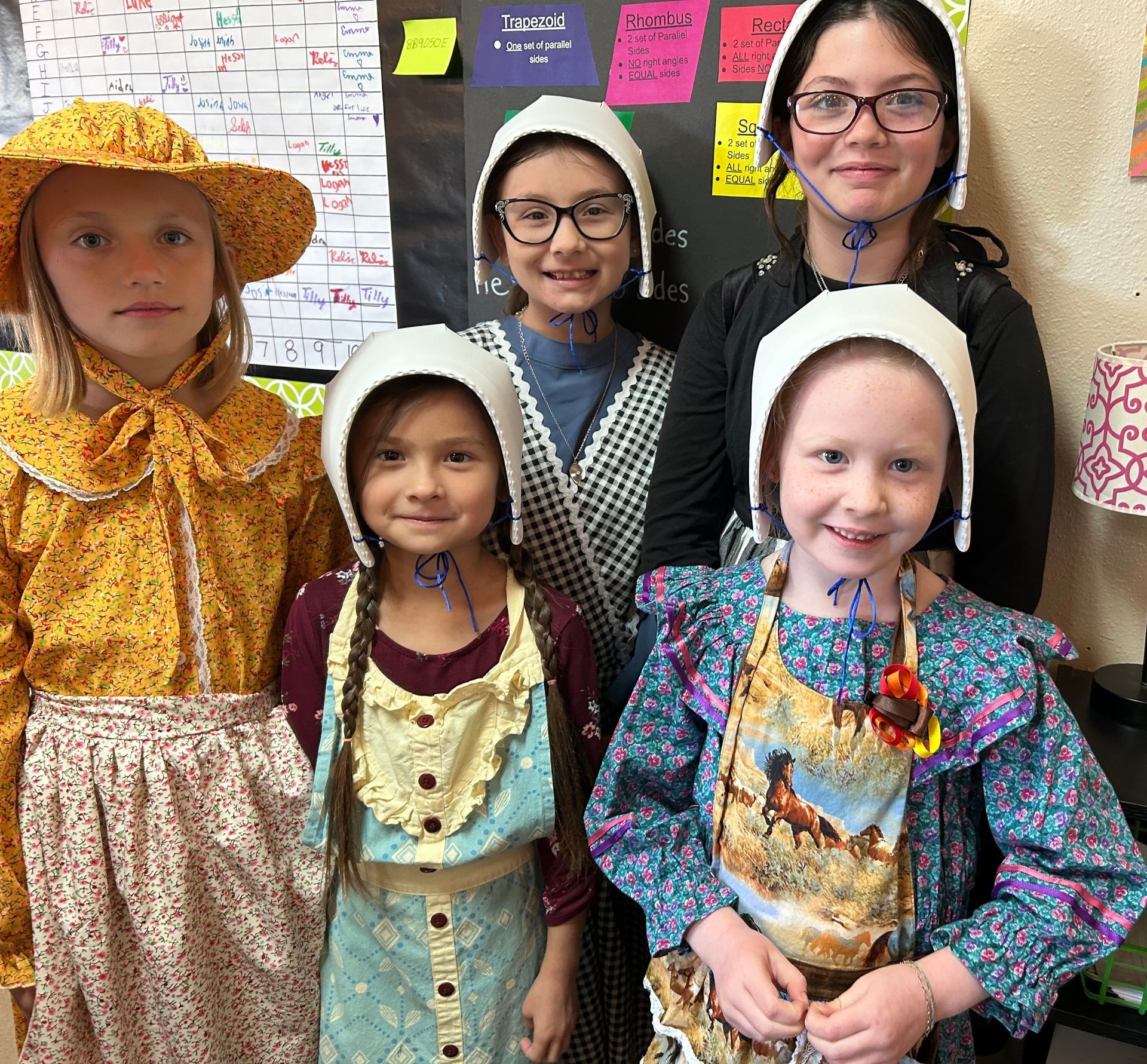 A group of young girls wearing hats and aprons pose for a picture