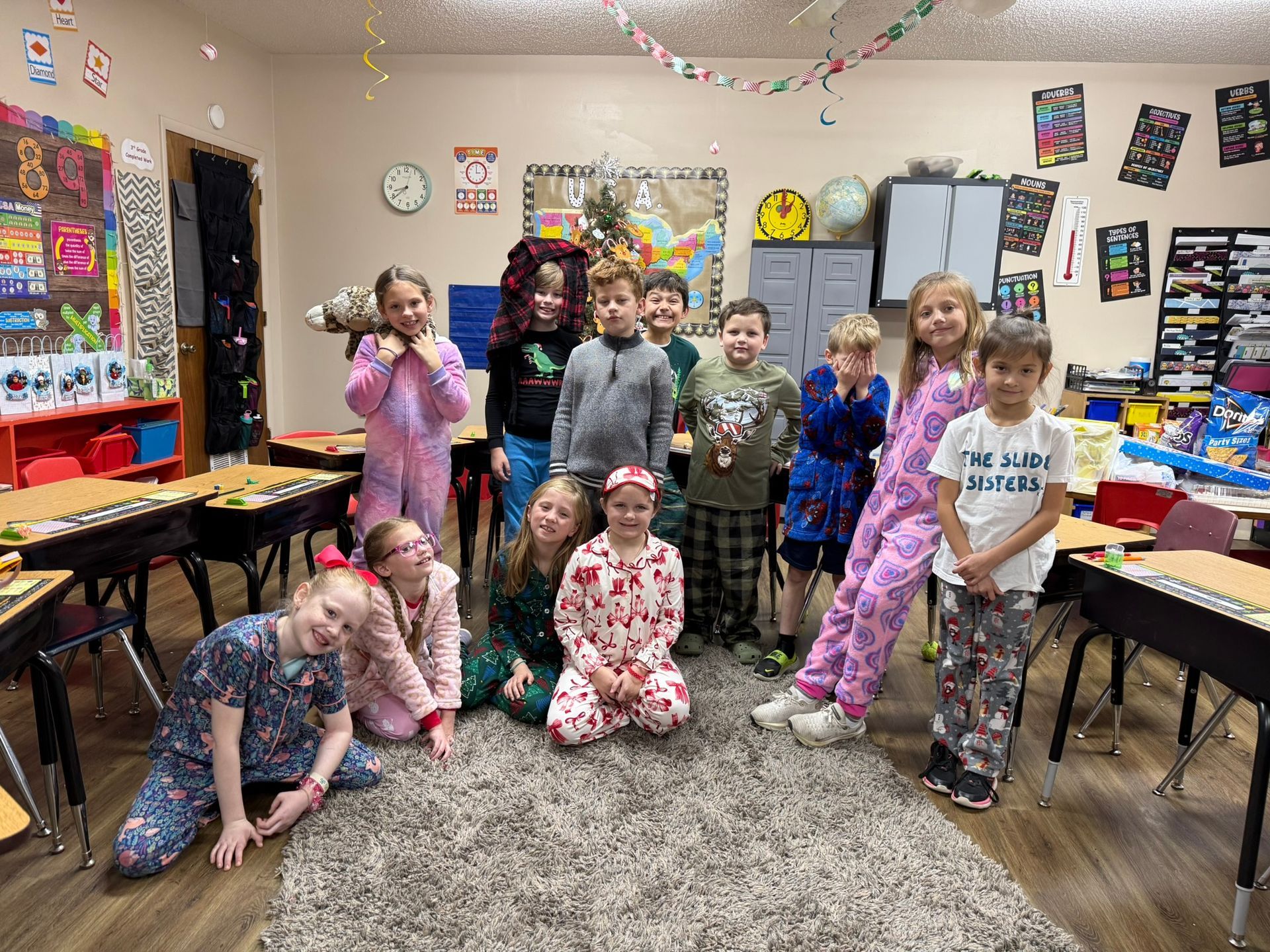 Children in pajamas pose in a decorated classroom.