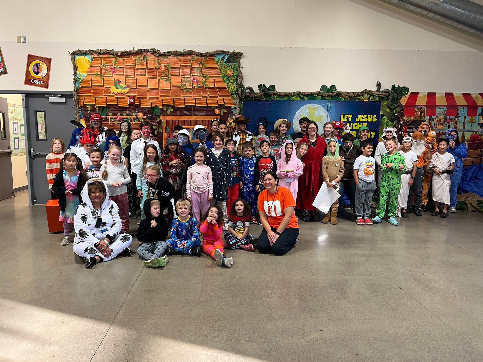 A group of children in pajamas are posing for a picture in a hallway.