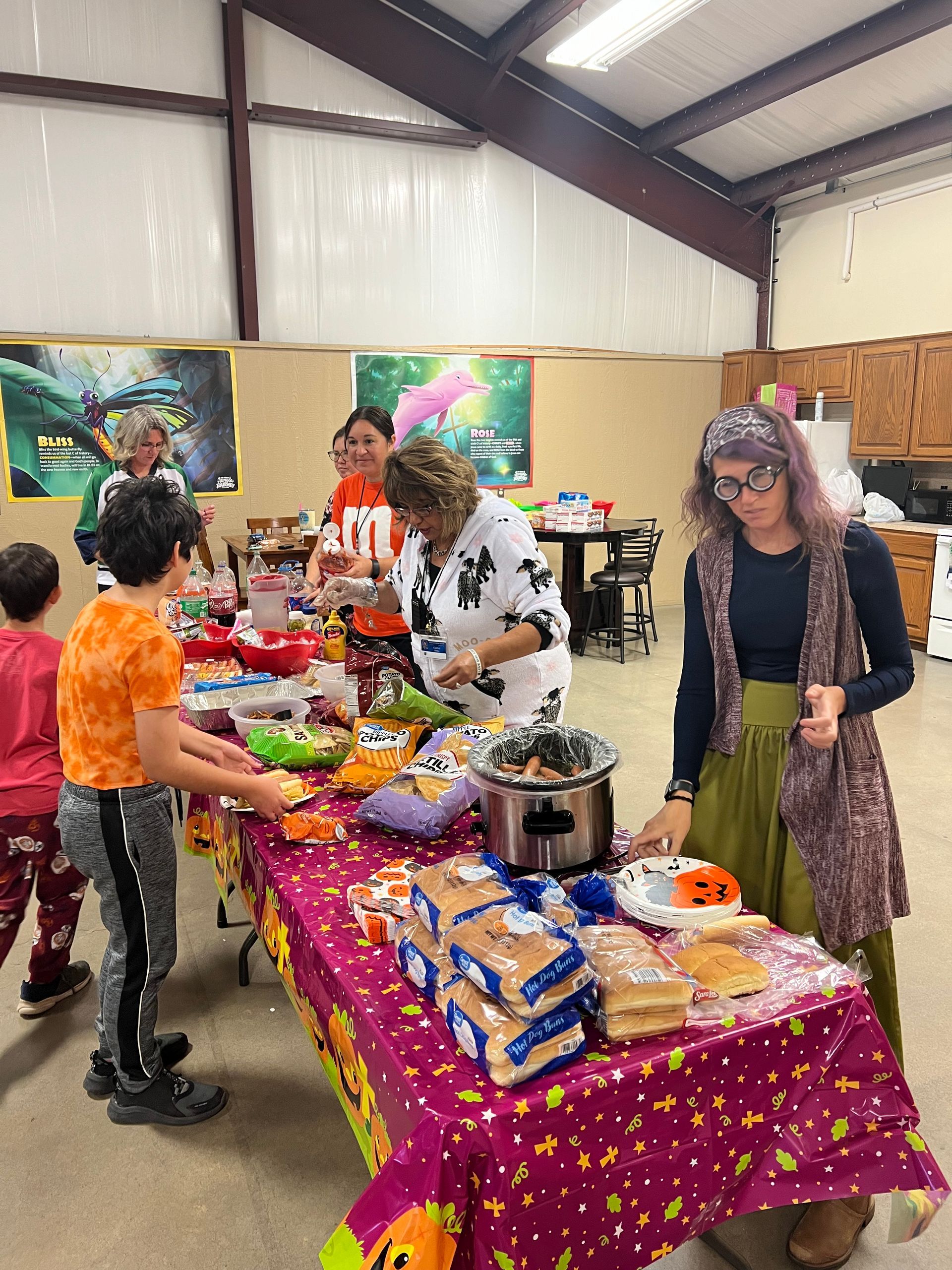 A group of people are standing around a table with food on it.