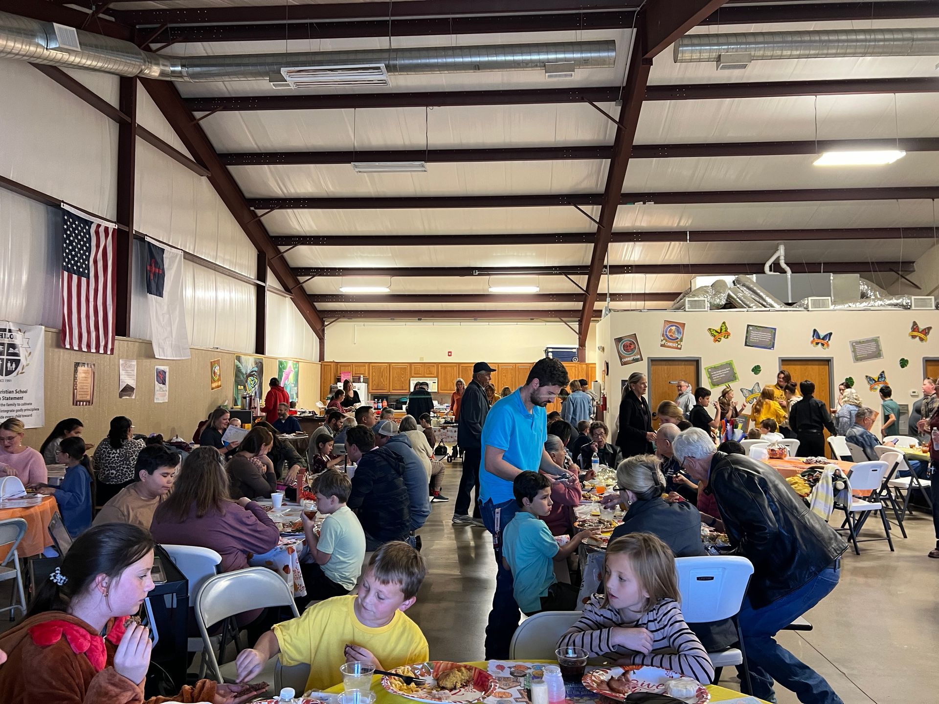 A large group of people are sitting at tables in a large room.