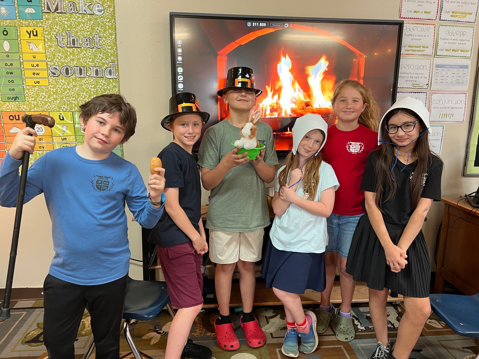 Group of students in hats posing, with fire backdrop.