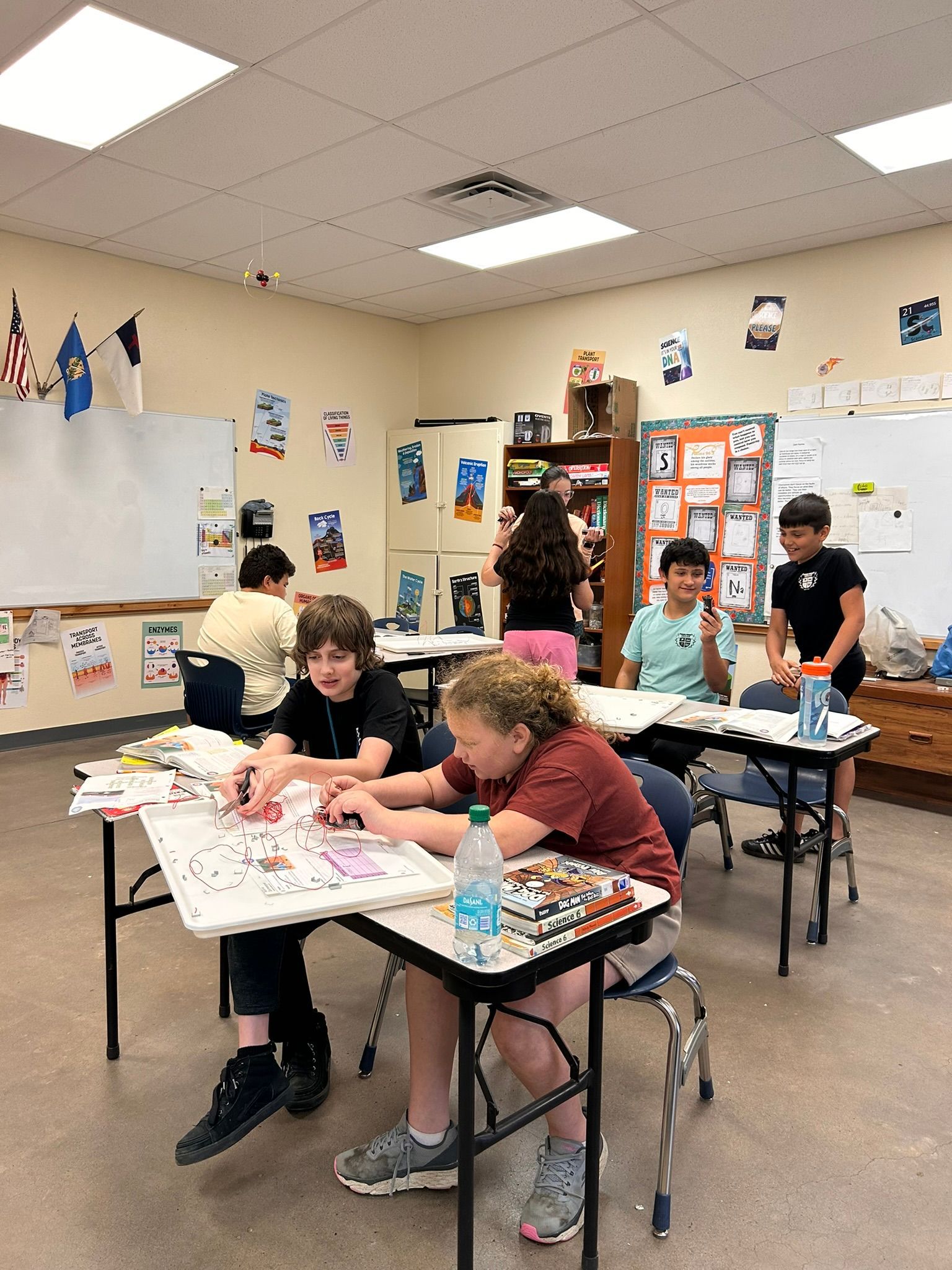 Students doing a classroom craft activity at tables with paper and supplies.