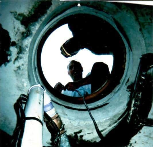 A man is looking through a hole in a pipe