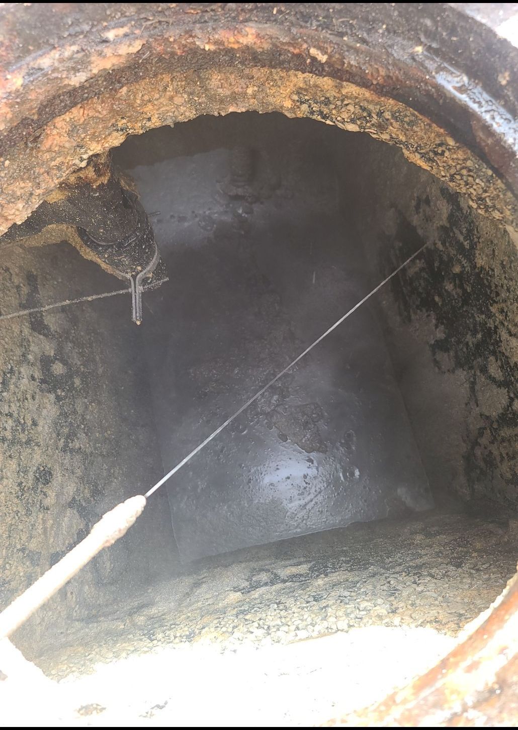 A manhole cover is being cleaned with a hose.