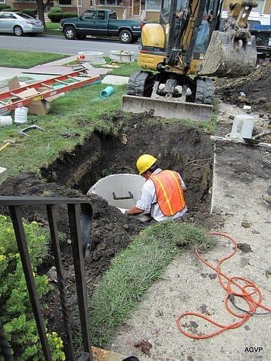 A man wearing a hard hat is digging a hole in the ground.