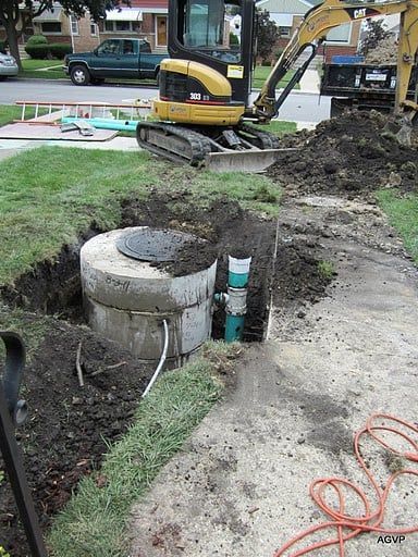 A bulldozer is digging a hole in the ground in front of a house.