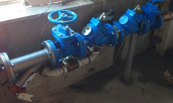 A bunch of blue valves are sitting on a pipe in a room.