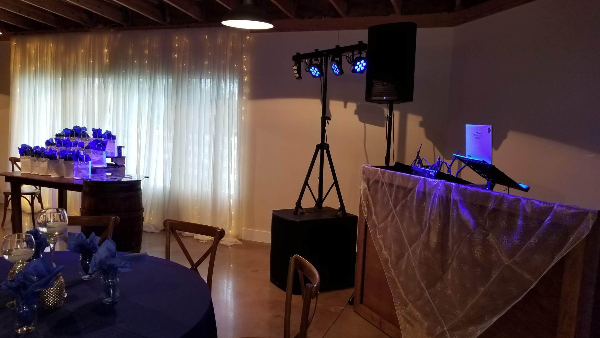 A room with tables and chairs and a dj set up.