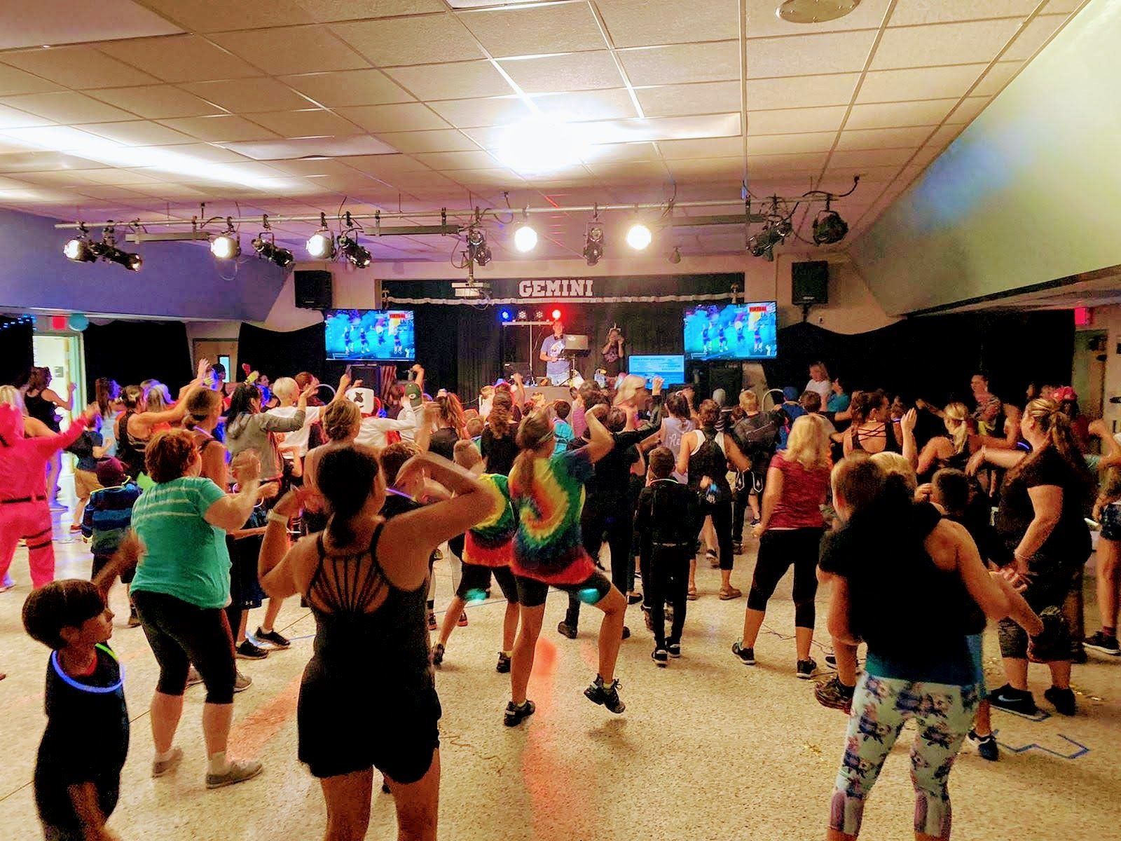A large group of people are dancing in a dance studio.