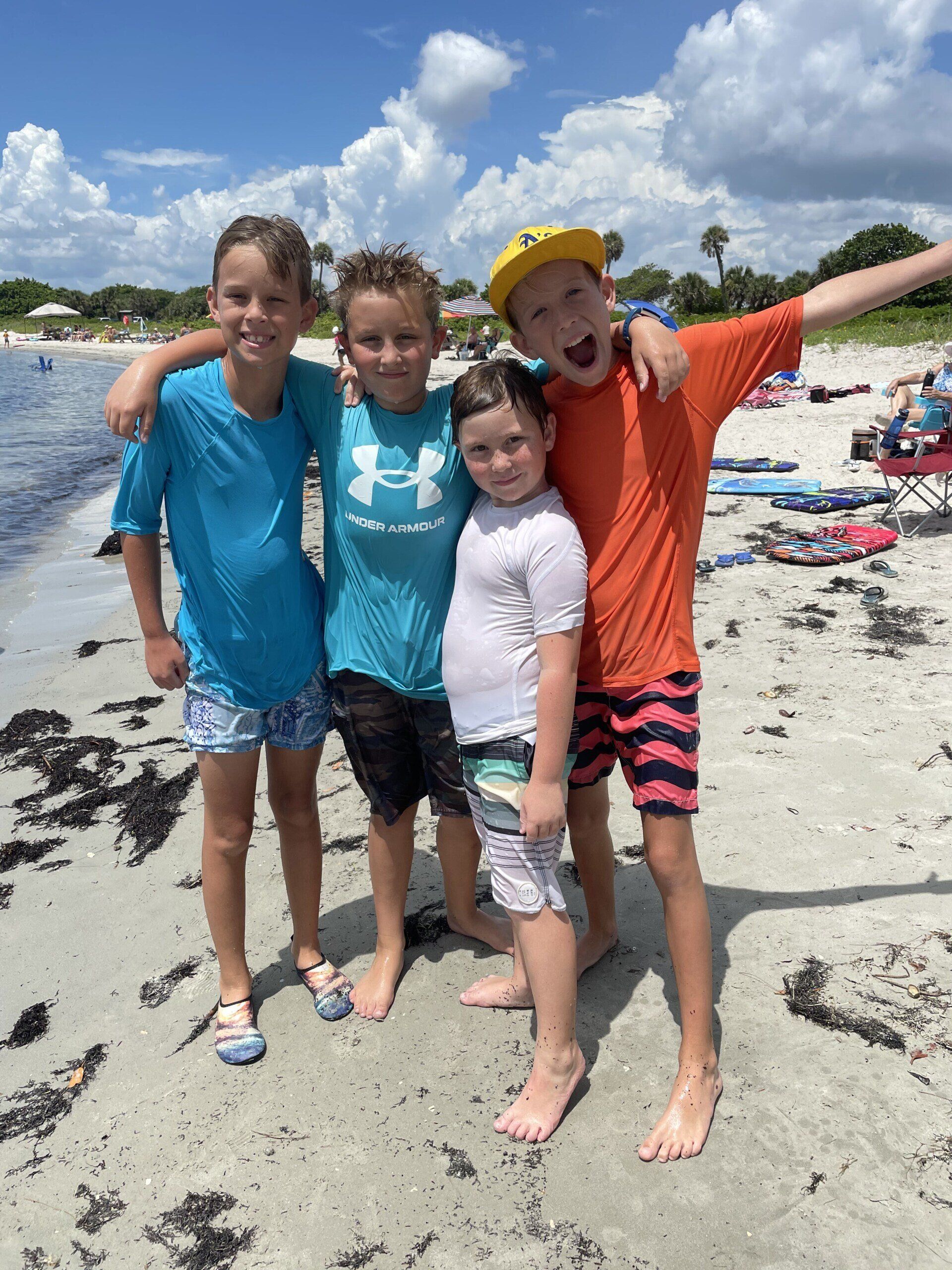 A group of children are posing for a picture on the beach.