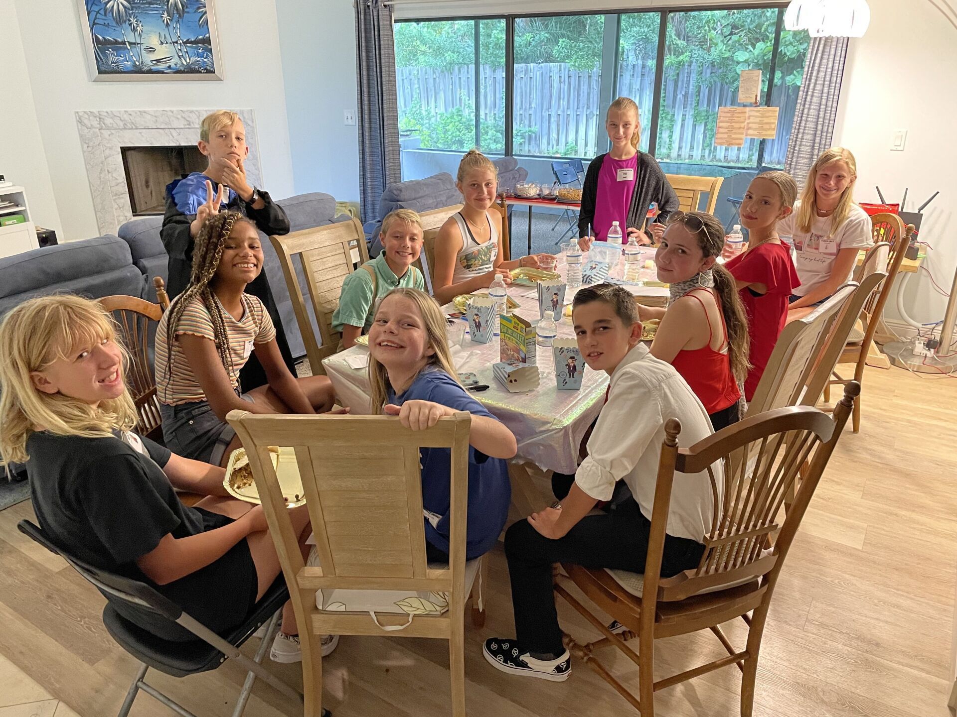 A group of children are sitting around a table in a living room.