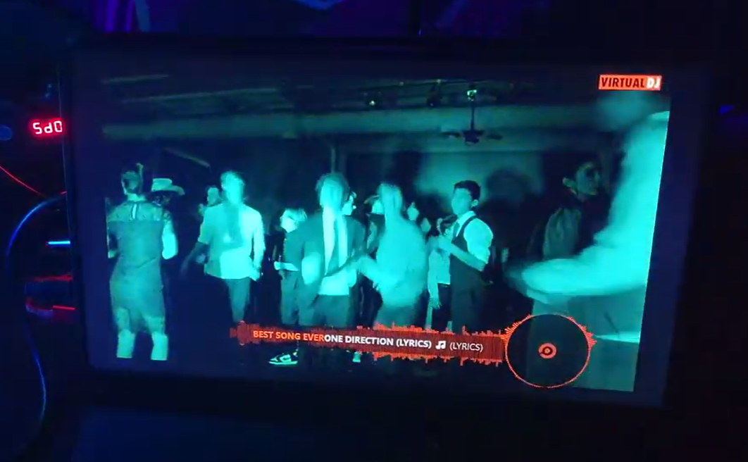 A group of people are dancing in a dark room on a television screen.