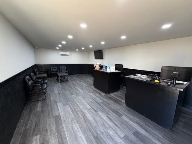 Empty waiting room with black chairs, dark desks, gray carpet, and recessed ceiling lights | Power Tire