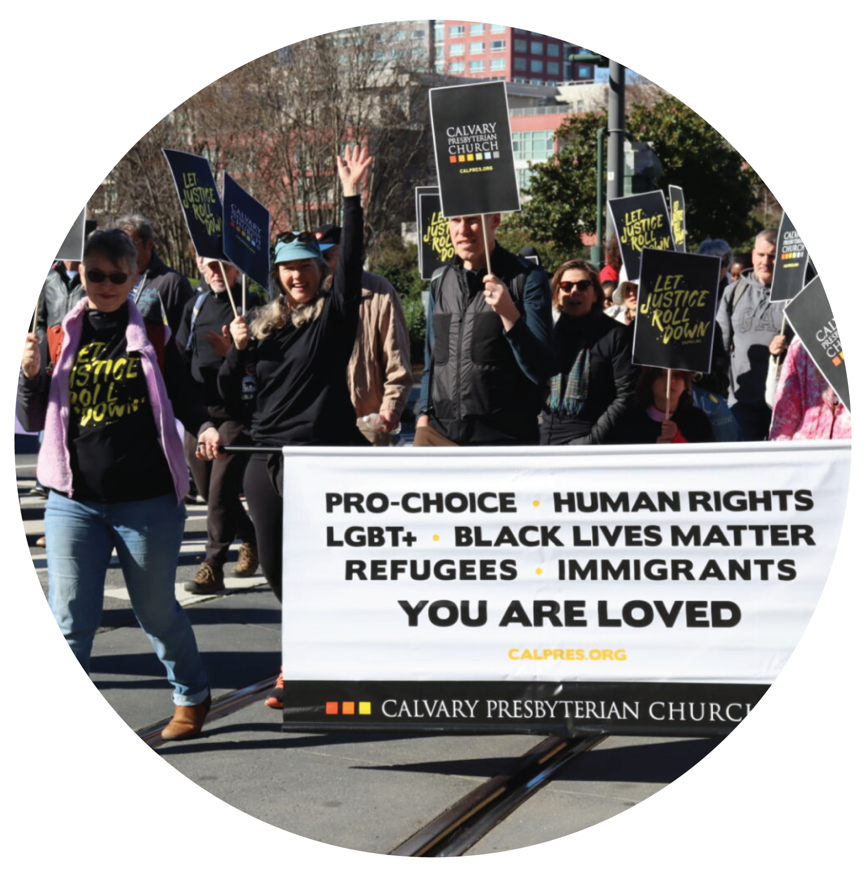 A group of Calvary folks marching in the 2025 MLK March - holding a banner and signs that say