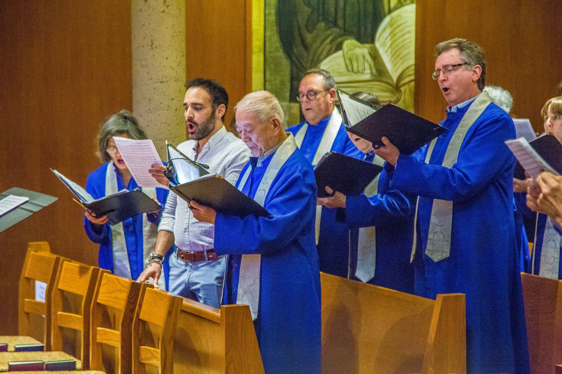 A group of choir members singing with the music in the pews of the Chapel