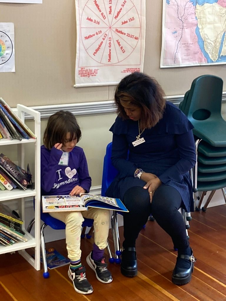 Childcare staff reading a book with one of the children at Calvary