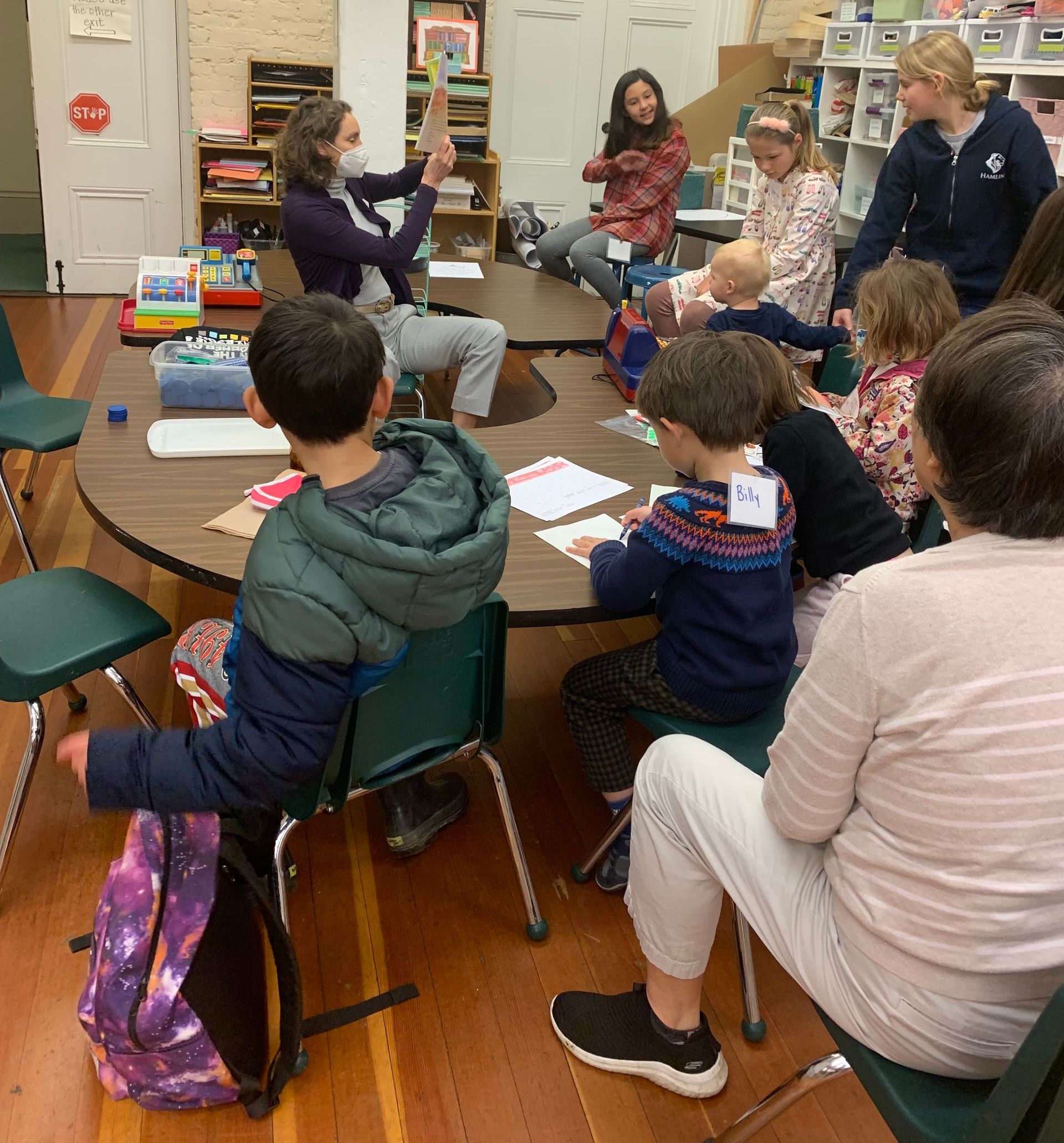 A bunch of children and teens of various ages doing activities in the lower level with Alison Faison
