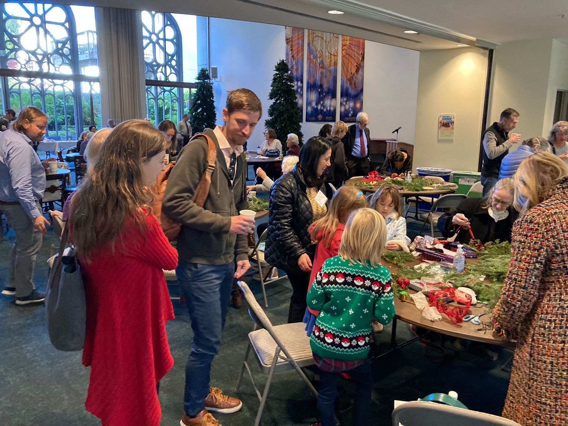 Families of all ages working on Advent wreaths with candles and holiday greens. 