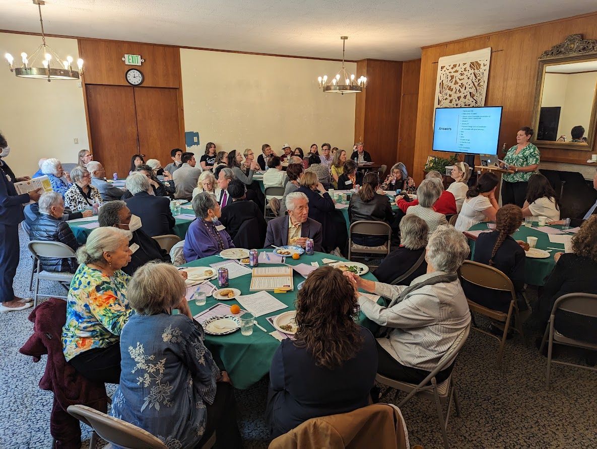 The Lounge filled with people eating lunch and watching the presenter, Jen Gee, talk about how difficult the citizenship test is.