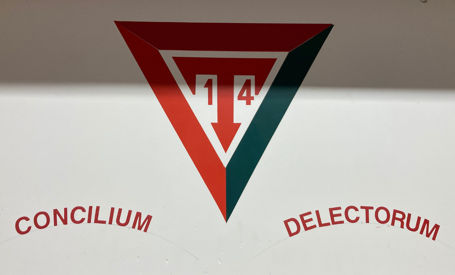 A faint image of the Troop 14 logo. It is a downward facing red and green triangle that has a T and 14 in it