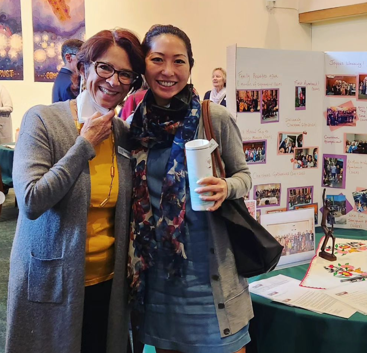 Two of our Living Sanctuary Ministry leaders standing in front of a poster board that shows the work the Living Sanctuary Team has done. This is in Calvin Hall during our Faith in Action Sunday event. They are smiling, one is holding a drink in her hand.