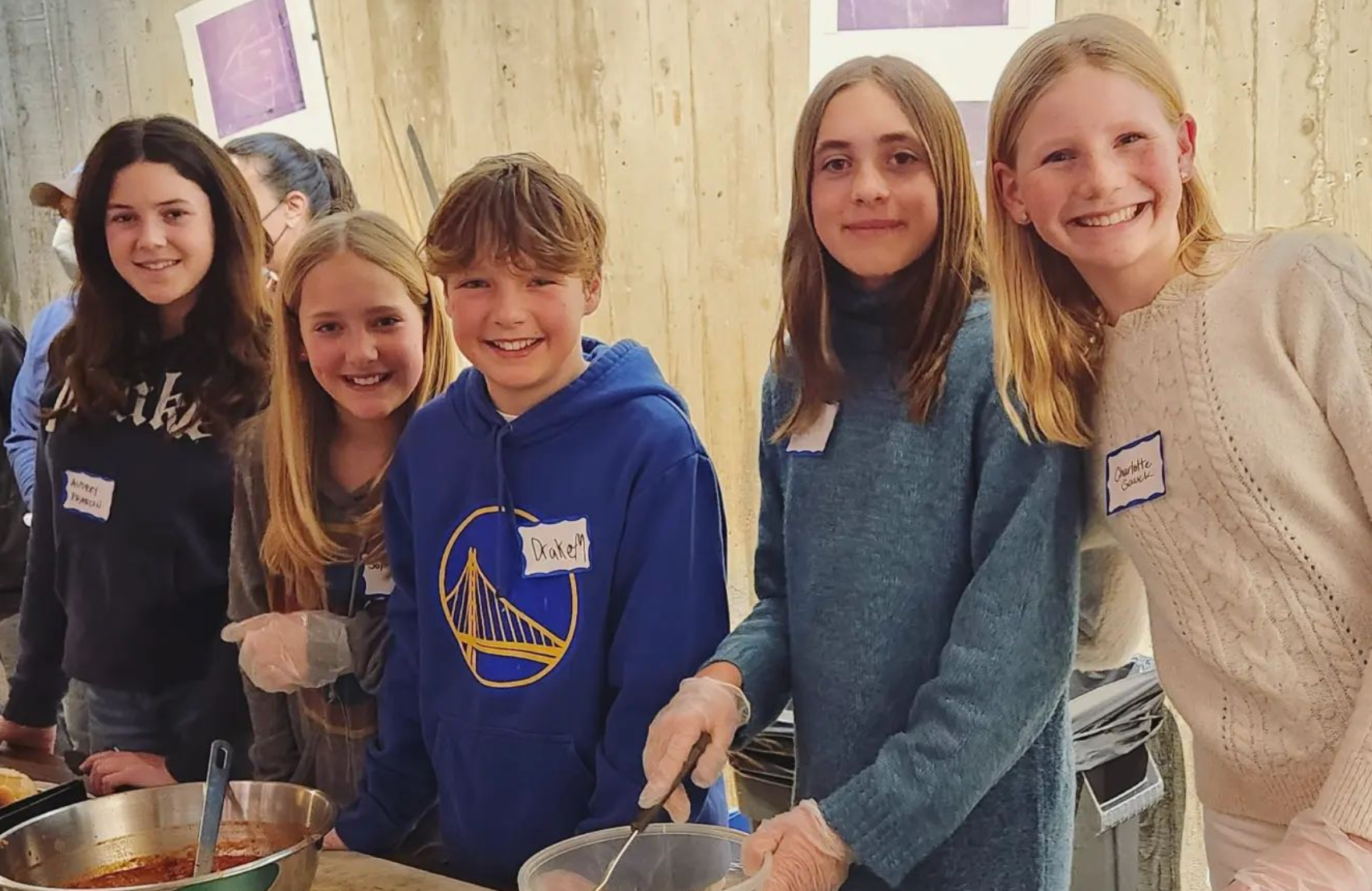 A group of teens, ages 10-15, serving food for a volunteer service opportunity