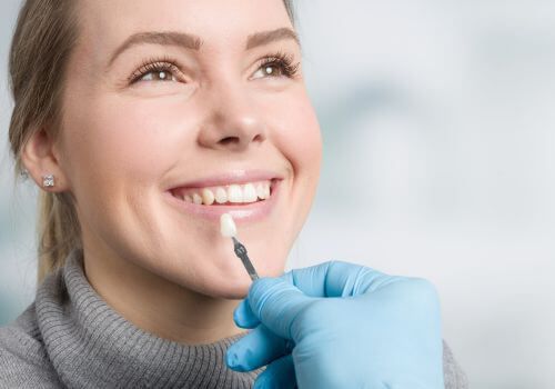 Woman smiling as a gloved hand applies a cosmetic treatment to her chin