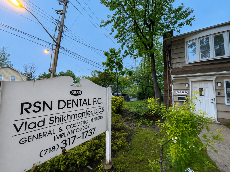 RSN Dental PC sign beside a house and trees at dusk, with phone number and practice name visible