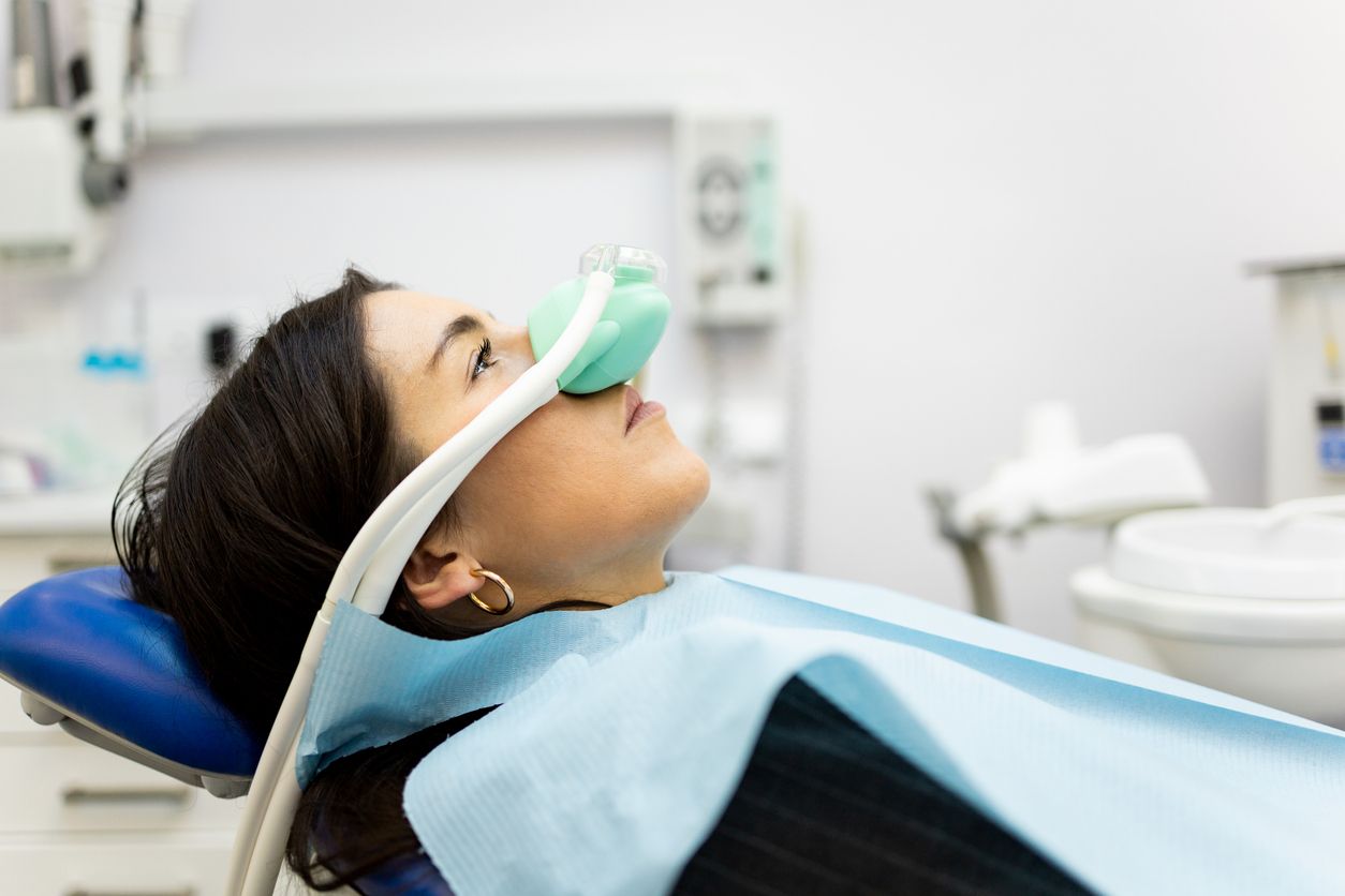 Patient reclining in a dental chair with oxygen mask in a clinic