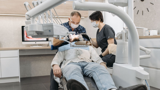 Dentist and assistant smiling with a child in a dental chair, showing a friendly clinic setting