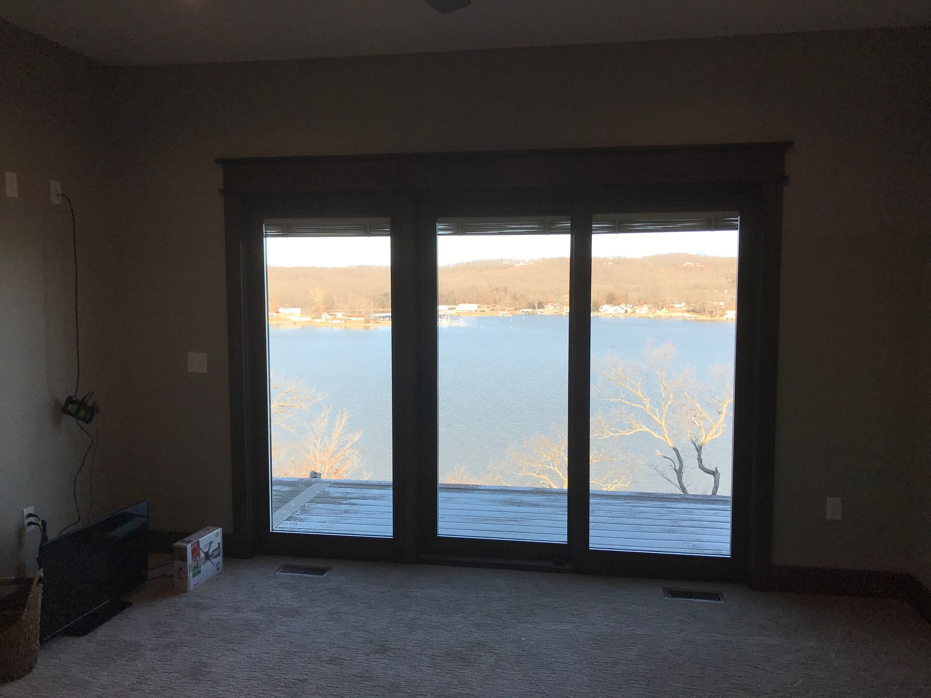 Empty living room with large picture windows overlooking a snowy lakeside view