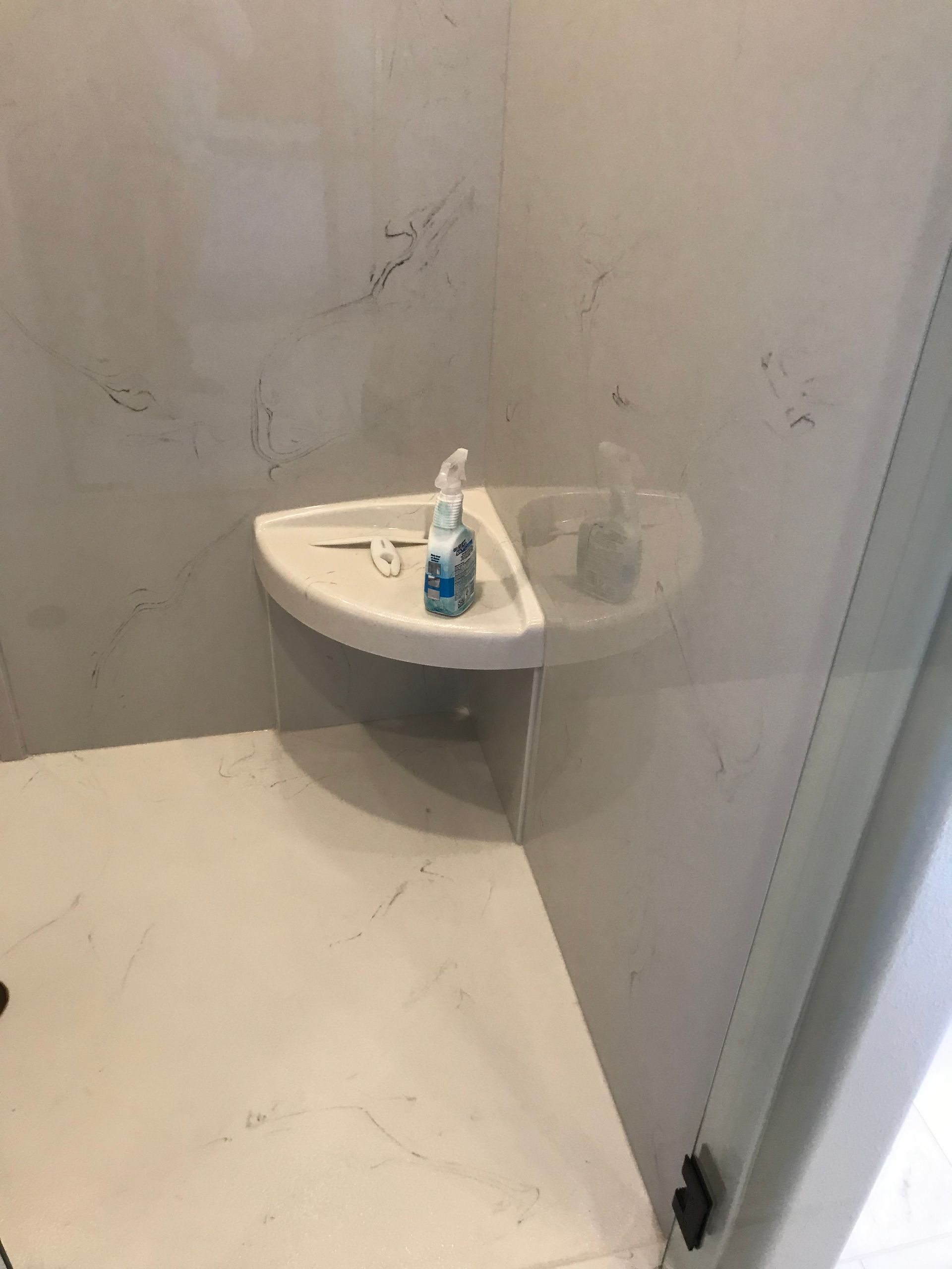 Small corner sink in a plain restroom with a soap dispenser on the counter and a closed door nearby