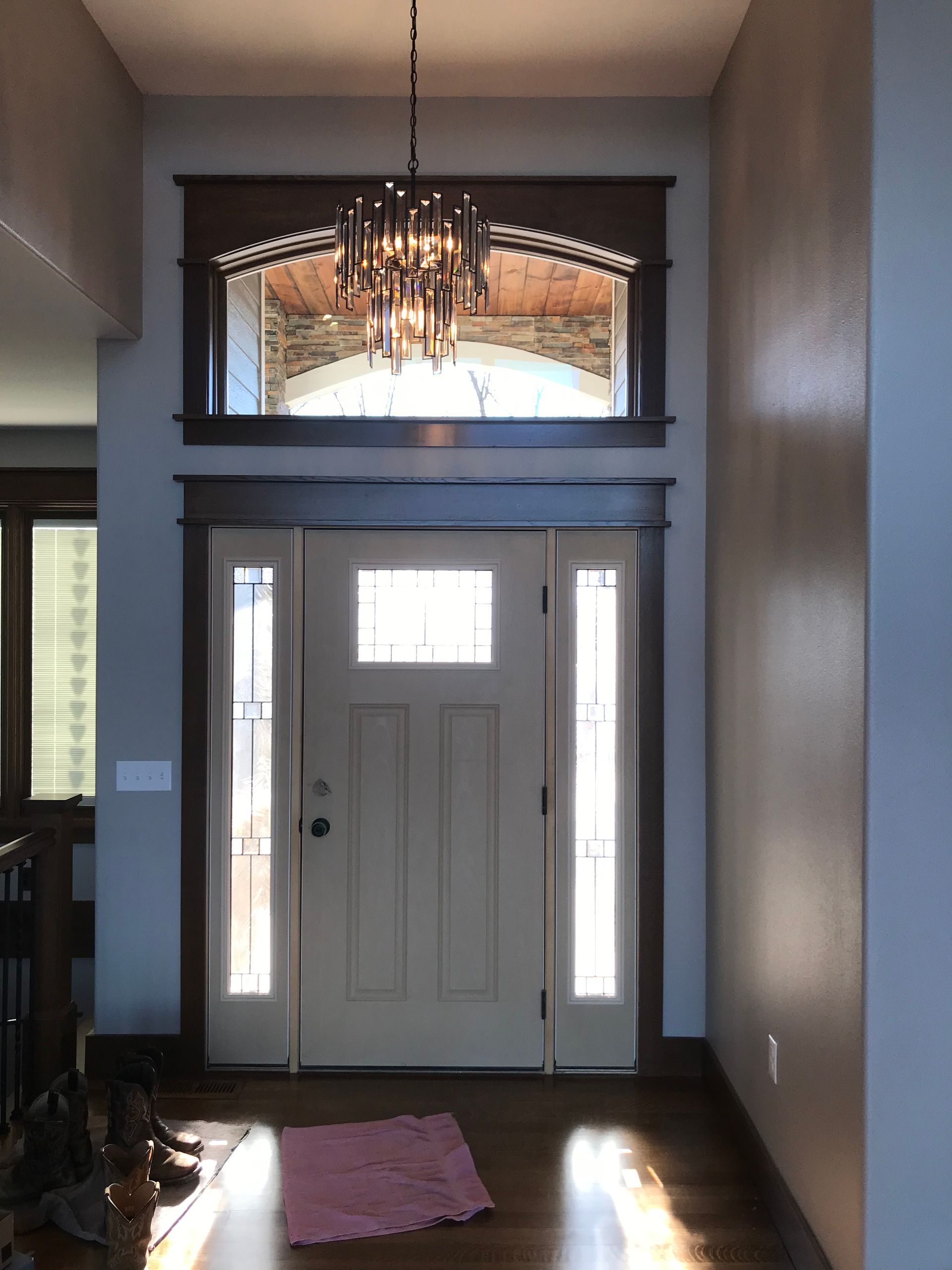 Front entryway with white door, sidelights, mirror above, and chandelier in a narrow hallway