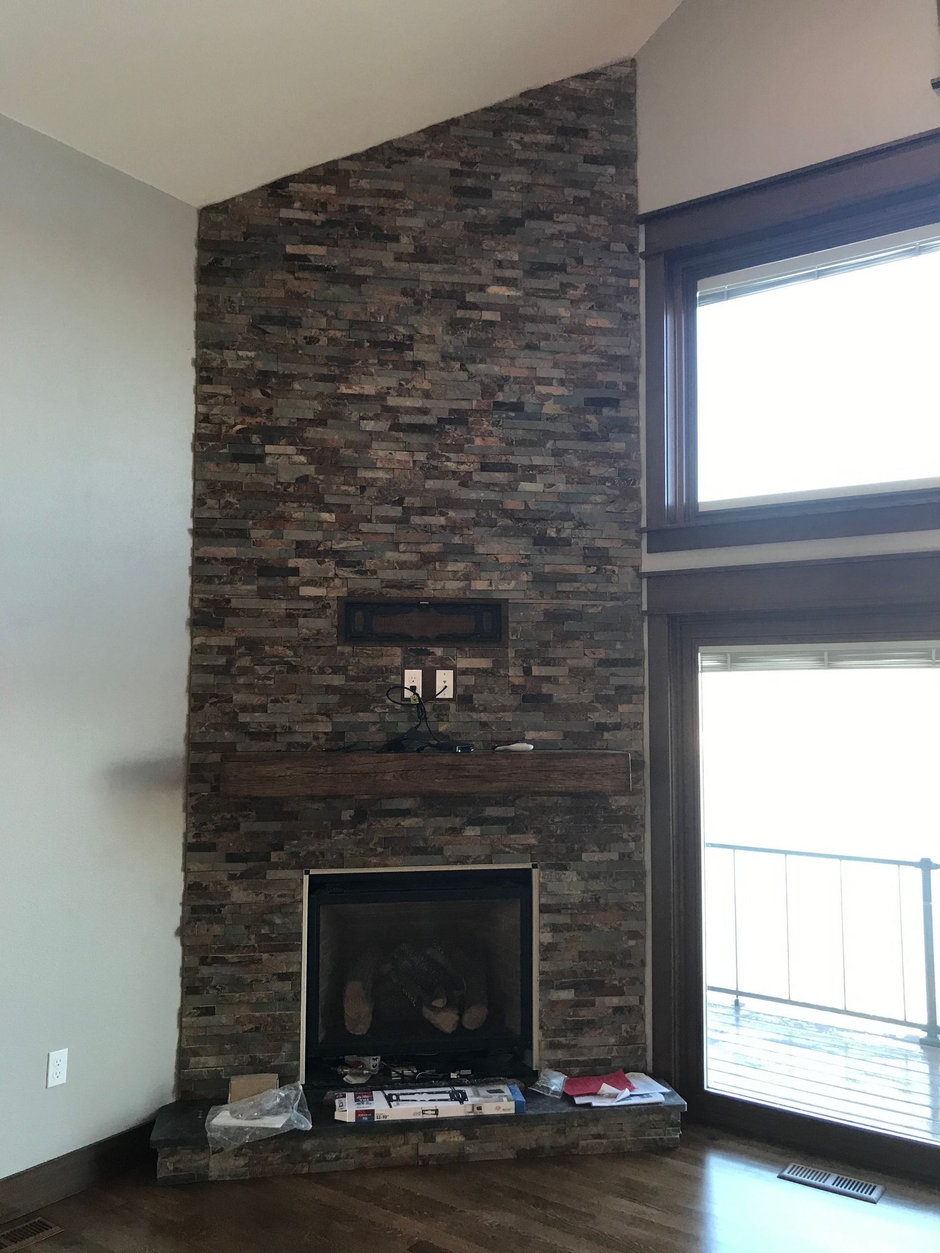 Living room corner with stone fireplace and large window letting in bright daylight
