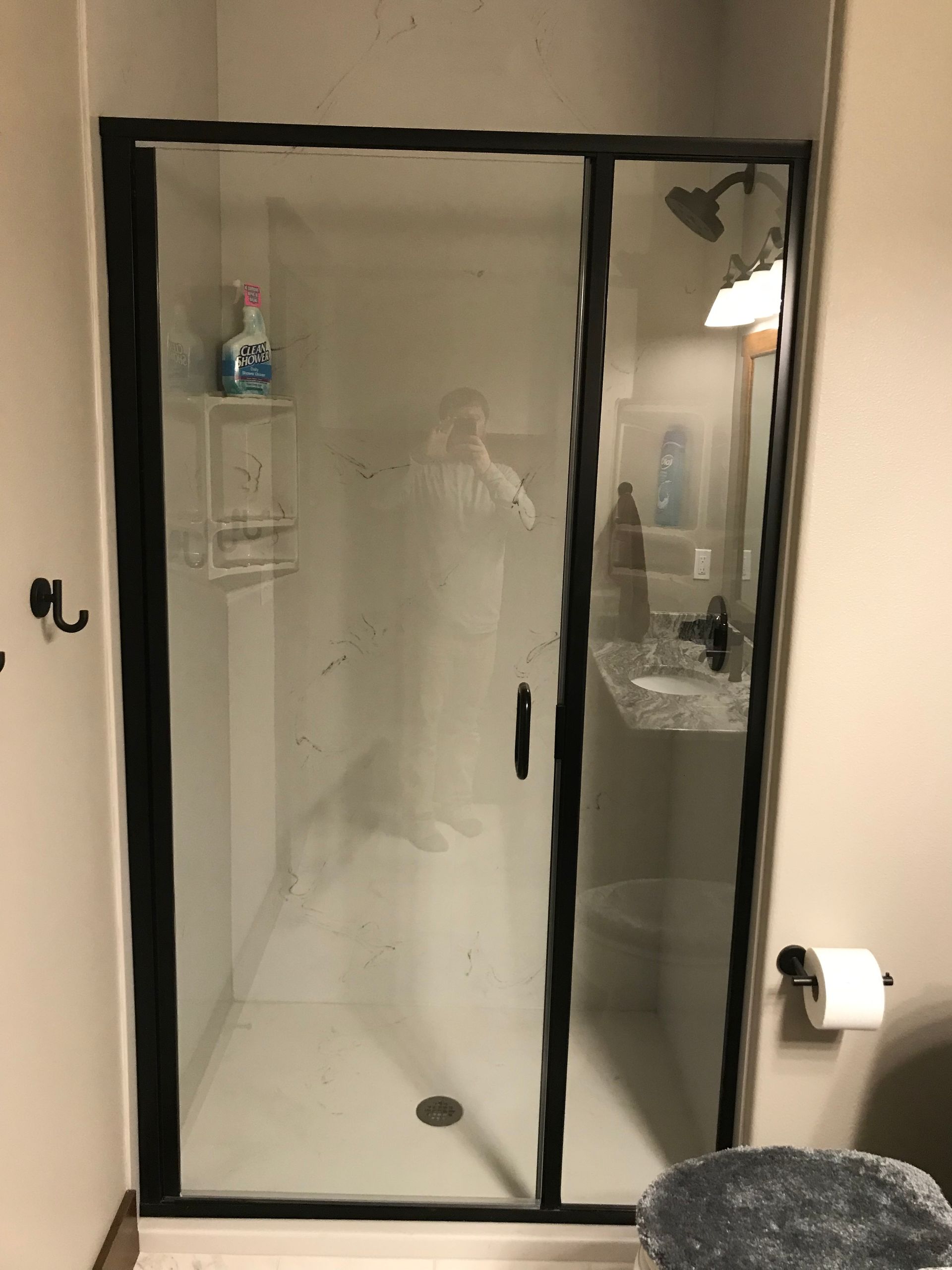 Bathroom shower stall with black-framed sliding glass door and built-in shelf