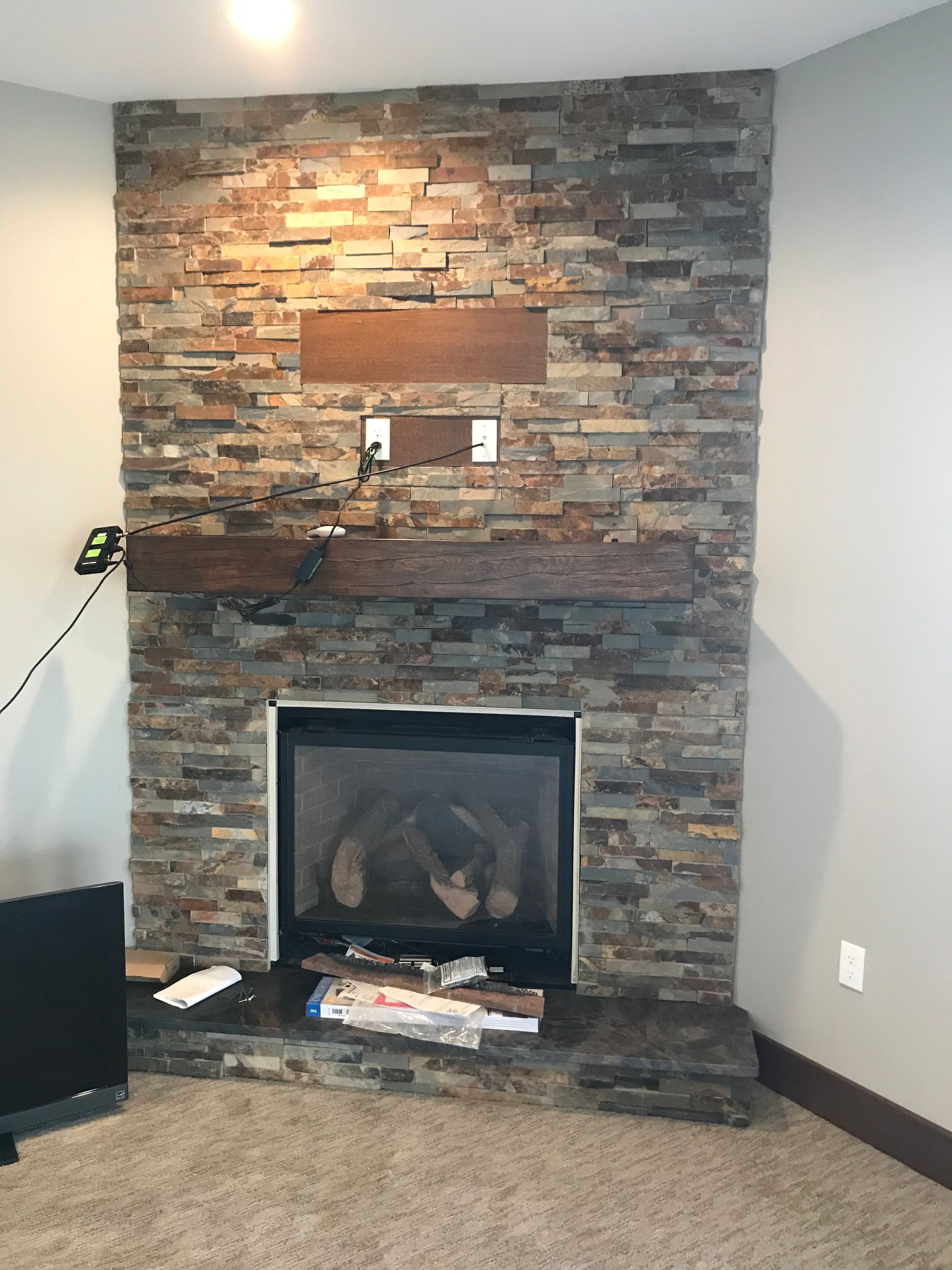 Living room fireplace with stacked stone surround, dark firebox, and tan carpet.