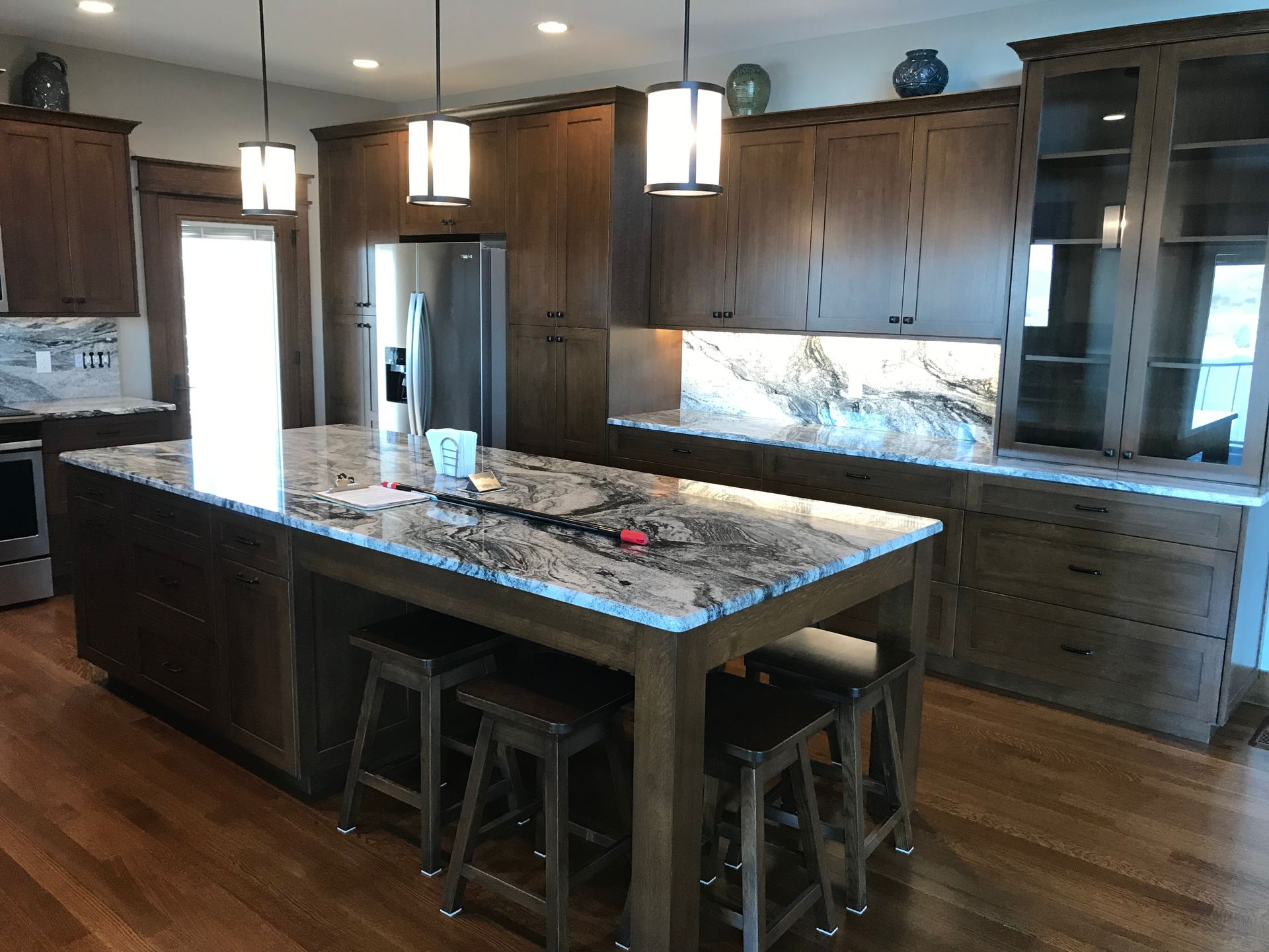 Modern kitchen with granite island, wood cabinets, stainless steel appliances, and pendant lights