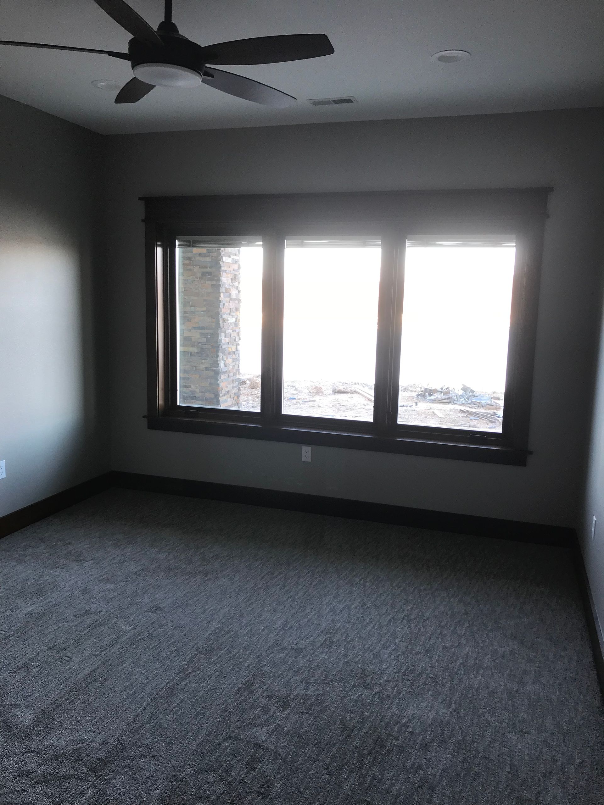 Empty carpeted room with ceiling fan and bright window