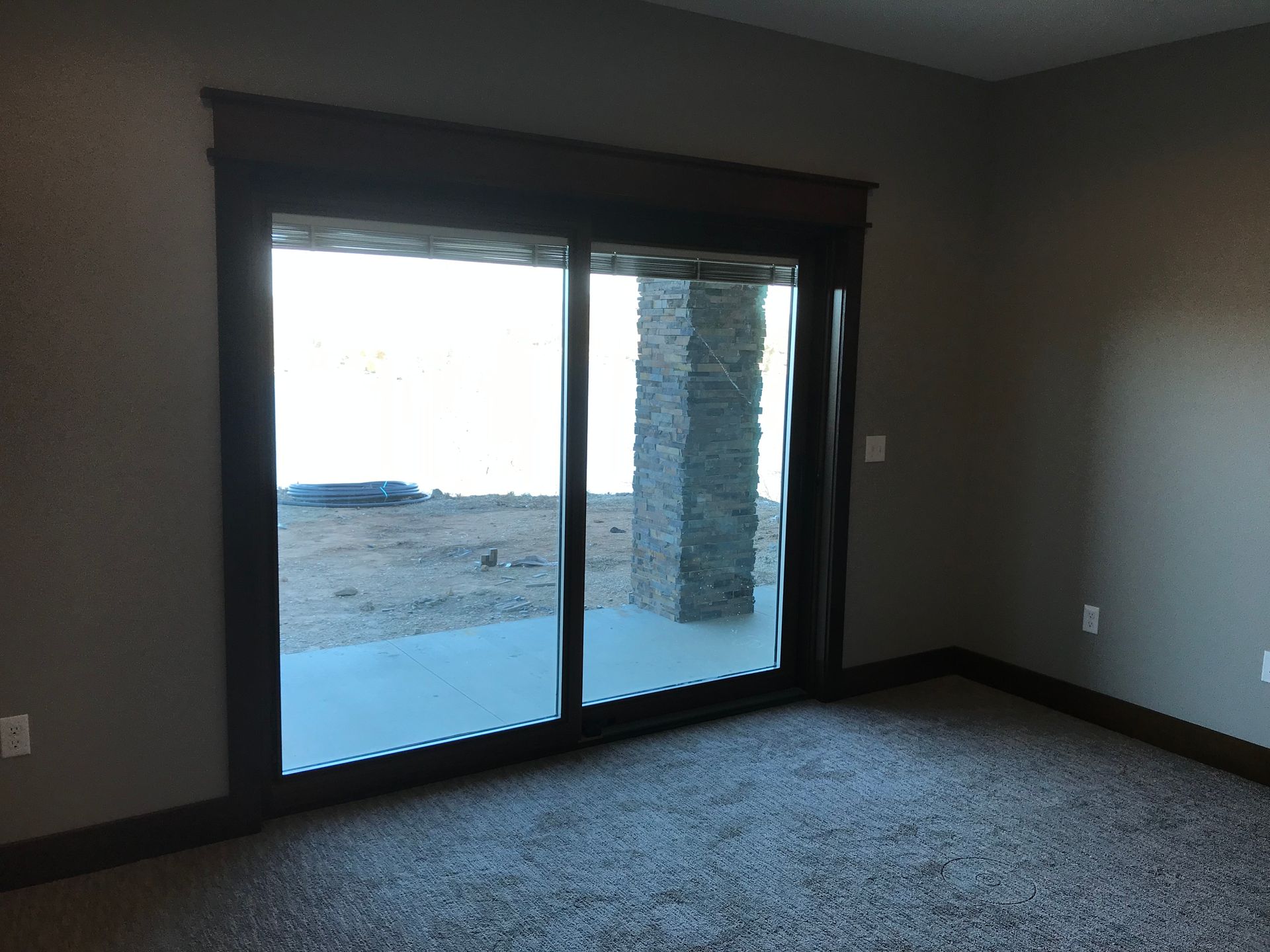 Empty room with gray carpet and a large sliding glass door leading outside