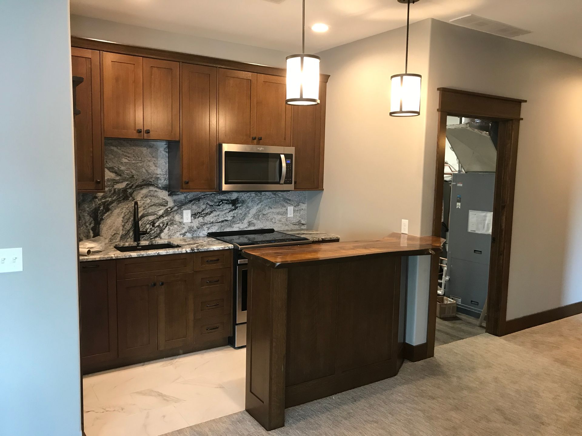 Modern kitchen with dark wood cabinets, granite counters, island, and pendant lights
