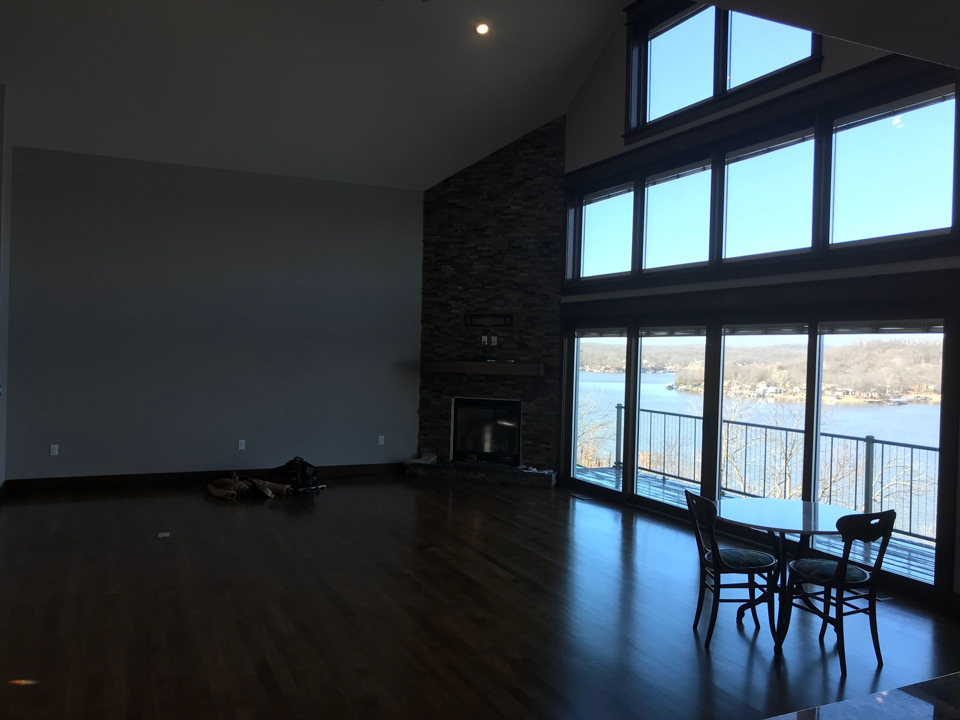Modern living room with dark wood floors, tall windows, fireplace, and a small table by the glass doors