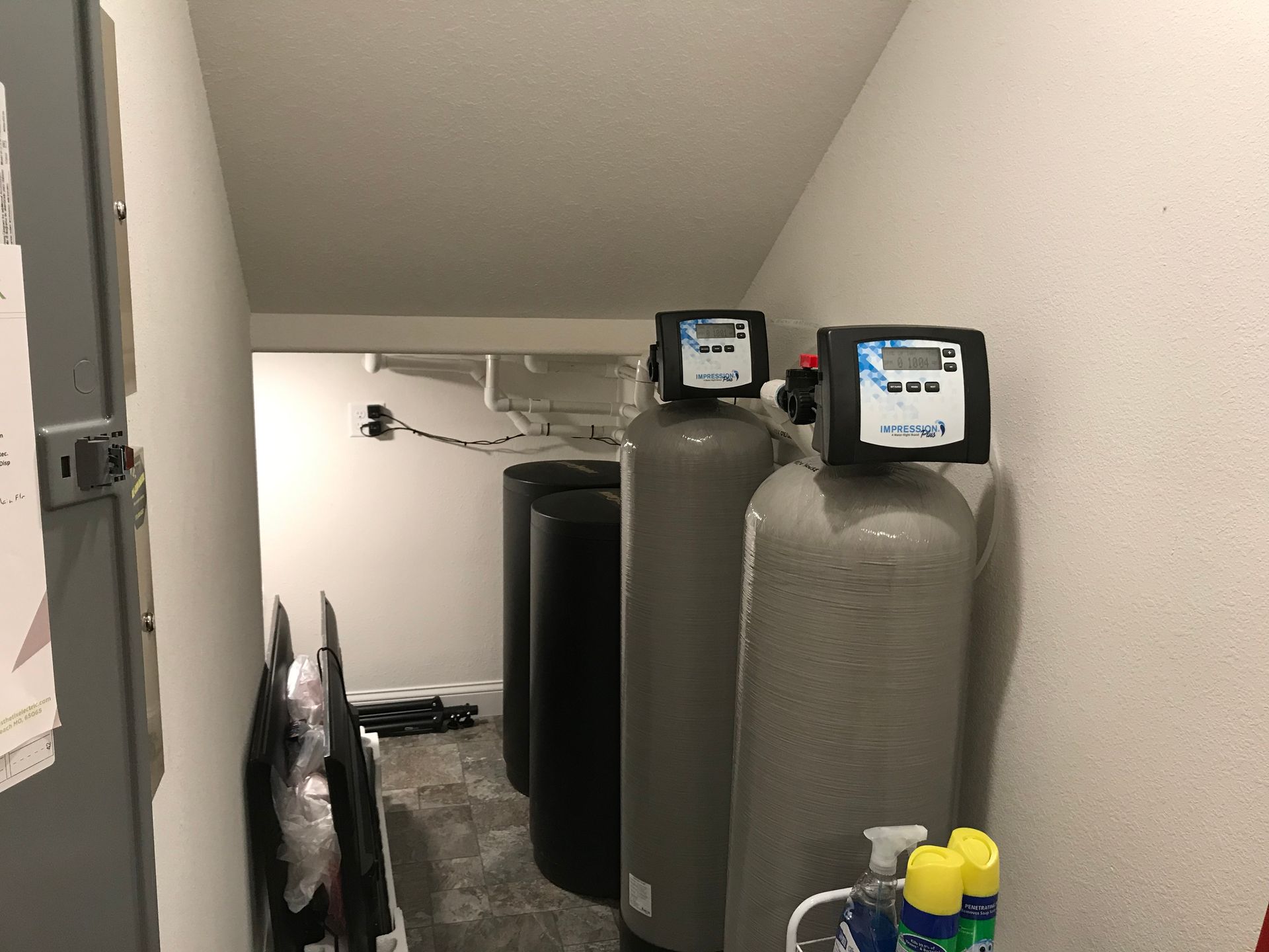 Basement utility room with large gray water tanks and equipment under sloped ceiling