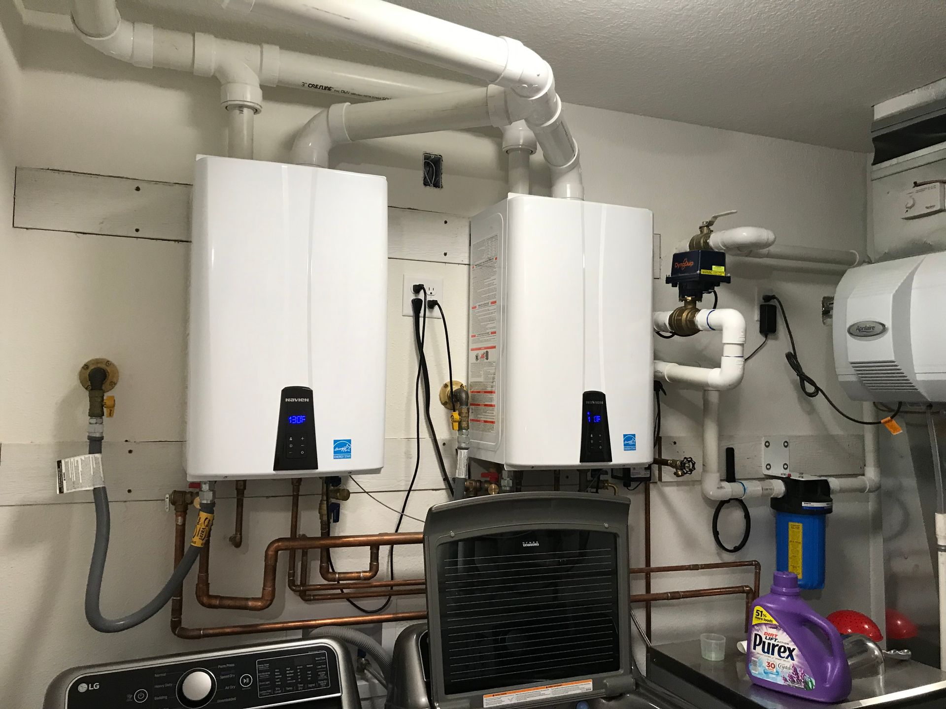 Utility room with two white wall-mounted boilers, pipes, and a water heater.