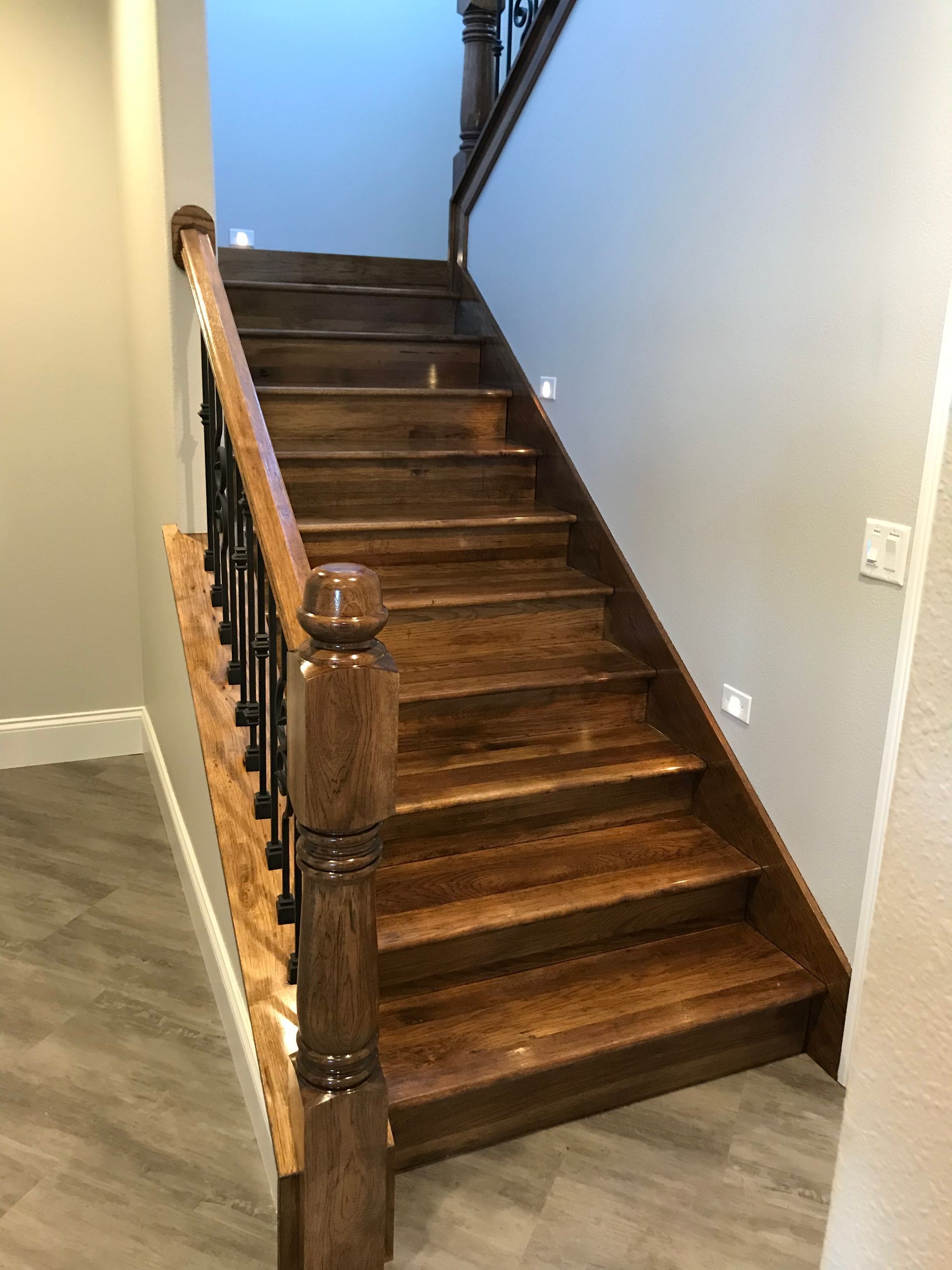Wooden staircase with dark railing in a carpeted interior hallway